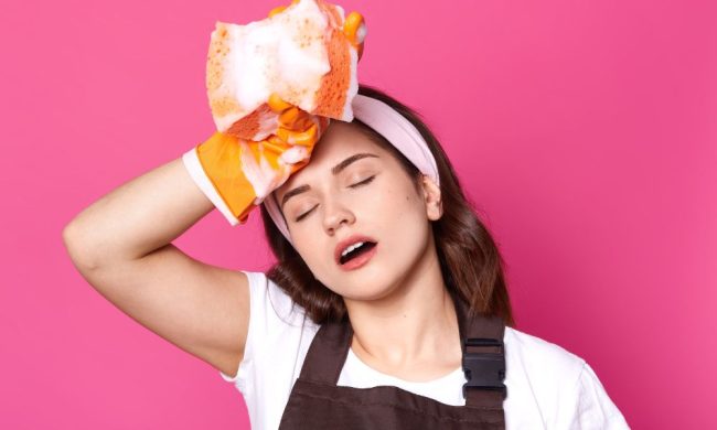 Donna stanca con spugna in mado, intenta a procedere con le pulizie in vacanza.