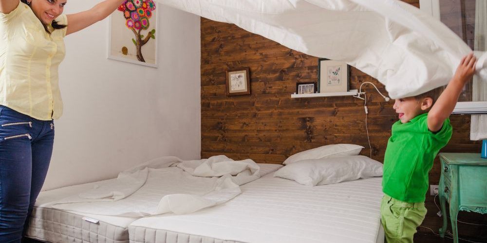 Donna e mambino che cambiano le lenzuola dopo aver pulito il materasso.