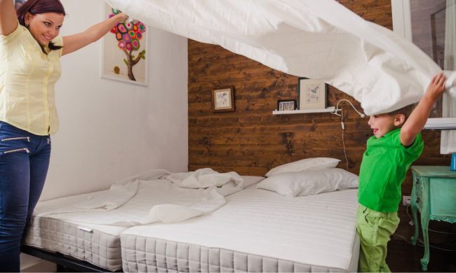 Donna e mambino che cambiano le lenzuola dopo aver pulito il materasso.