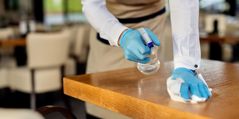 closeup-waiter-disinfecting-cafe-tables-after-work Addetto alla Pulizia professionale dei ristoranti