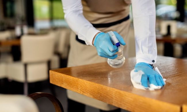 closeup-waiter-disinfecting-cafe-tables-after-work Addetto alla Pulizia professionale dei ristoranti